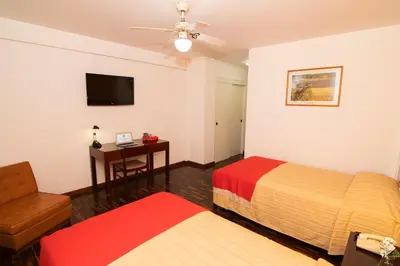 a hotel room with two beds and a chair and a table at Hotel Chavín in Barranca