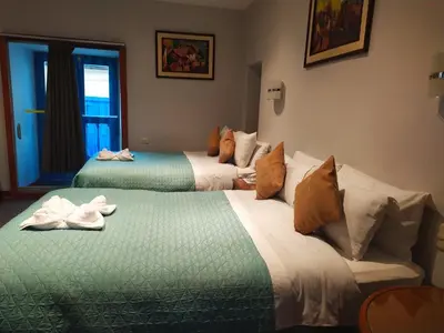 two beds in a hotel room with towels on them at HOTEL AMTALLPA San Blas Inn in Cusco