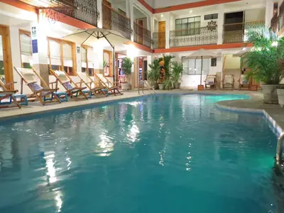 a large swimming pool in a hotel with rocking chairs at Hotel Las Flores in Ica