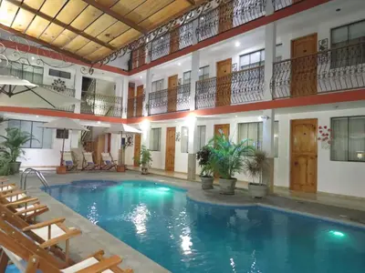 a large swimming pool in a building with chairs at Hotel Las Flores in Ica