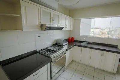 a kitchen with white cabinets and a stove top oven at Oceanfront Penthouse in Miraflores in Lima