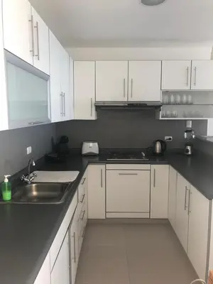 a kitchen with white cabinets and a sink at Paracas departamento Condominio Nautico in Paracas