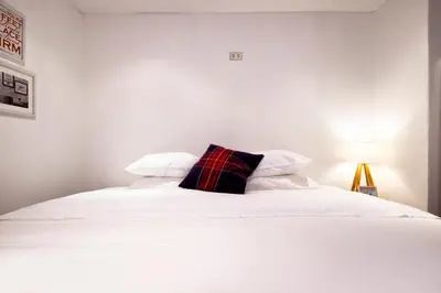 a white bed with a plaid pillow on it at InkaHuset Pacasmayo in Lima