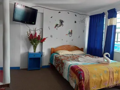 a bedroom with a bed and a tv on the wall at Posada Azul Cusco in Cusco