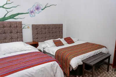 a bedroom with two beds and a painting on the wall at Magic Cusco in Cusco