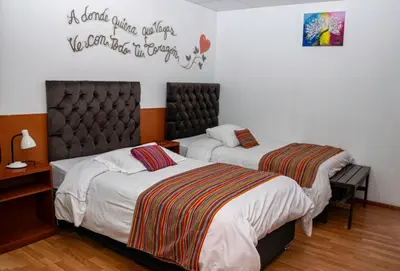 a bedroom with two beds and a sign on the wall at Magic Cusco in Cusco