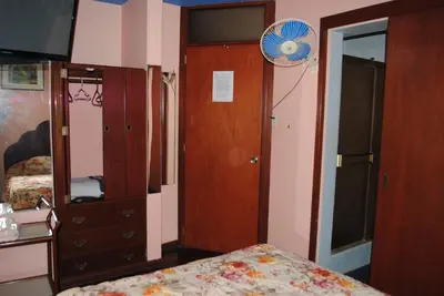 a bedroom with a bed and a dresser and a fan at Hotel SKY in Lima