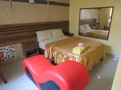 a red chair in a bedroom with a bed and a mirror at HOTEL ESTRELLA in Lima