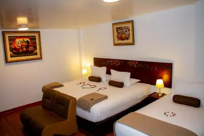 a hotel room with two beds and a chair at Hotel Retama Machupicchu in Machu Picchu