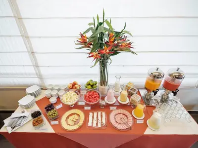 a table with food and drinks and a vase of flowers at Qorianka Hotel in Lima