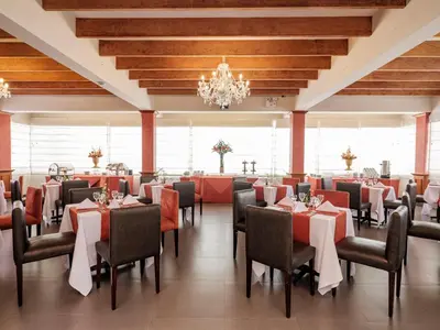 a dining room with tables and chairs and a chandelier at Qorianka Hotel in Lima