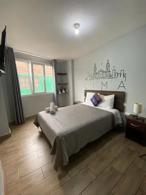 a bedroom with a large bed and a wooden floor at Lima Airport Tampu in Lima