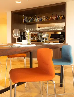 a bar with two chairs and a counter with wine glasses at Xima Lima San Isidro in Lima
