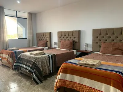 a hotel room with two beds and a window at Huacachina Desert House in Ica