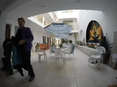 a woman walking in a room with chairs and tables at Paracas Backpackers House in Paracas