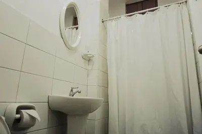 a bathroom with a white shower curtain and a sink at Hospedaje El Velero in Paracas