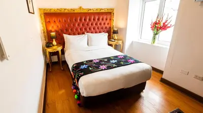 a bedroom with a large bed with a wooden headboard at Auka Boutique San Blas in Cusco