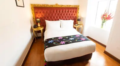 a bedroom with a large bed with a red headboard at Auka Boutique San Blas in Cusco