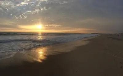 a beach with the sun setting on the ocean at Surfari Punta Rocas in Punta Negra
