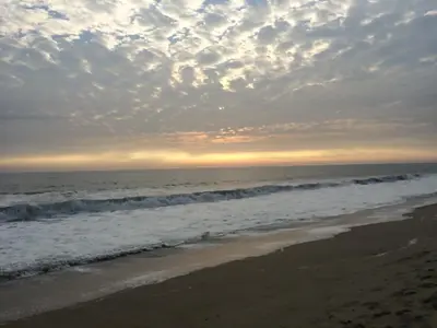 a beach with a cloudy sky and the ocean at Surfari Punta Rocas in Punta Negra
