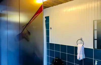 a bathroom with a shower and a blue tiled wall at Surfari Punta Rocas in Punta Negra