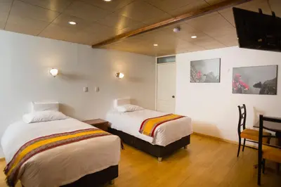 a bedroom with two beds and a table and a chair at MOAF Cusco Boutique Hotel in Cusco