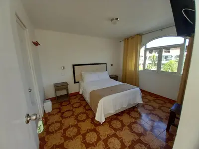 a bedroom with a large bed and a window at Hostal Los Frayles in Paracas