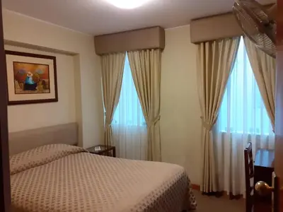 a bedroom with a bed and two large windows at Hotel Melodia in Lima