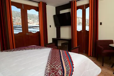 a bedroom with a bed and a tv and windows at Altipacha Ayacucho Hotel in Ayacucho