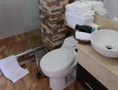 a bathroom with a toilet and a sink and towels at Altipacha Ayacucho Hotel in Ayacucho