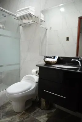a white bathroom with a toilet and a sink at Altipacha Ayacucho Hotel in Ayacucho