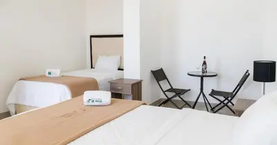 a room with two beds and a table and chairs at Hotel Residencial Los Frayles in Paracas