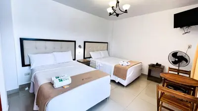 a hotel room with two beds and a television at Hotel Residencial Los Frayles in Paracas