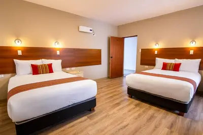 a hotel room with two beds and wooden floors at Hotel San Pedro Plaza in Cusco