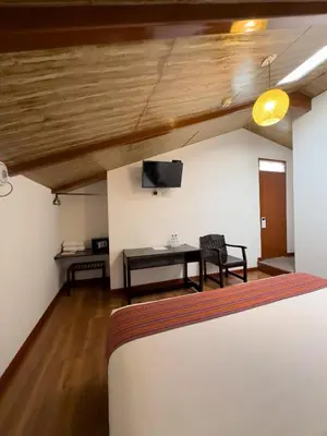 a room with a bed and a table and a tv at Hotel San Pedro Plaza in Cusco