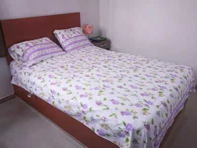 a bed with a white comforter with purple flowers at Hospedaje Villa Del Sol in Ica