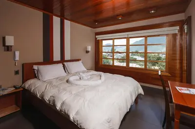 a bedroom with a white bed with a window at Hotel Heidinger in Oxapampa