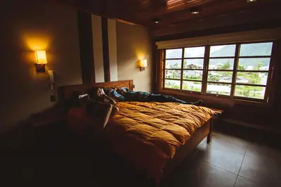 a person laying on a bed in a room with a window at Hotel Heidinger in Oxapampa