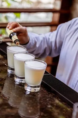 a man is pouring milk into three glasses on a counter at Casa del Sol Machupicchu in Machu Picchu