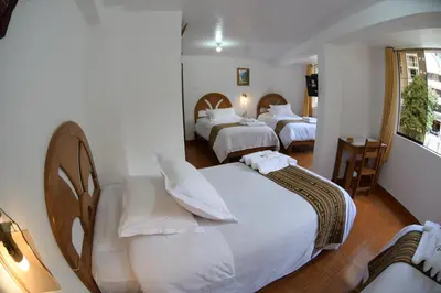 a hotel room with two beds with white sheets at MAPILAND- Hotel Boutique in Machu Picchu