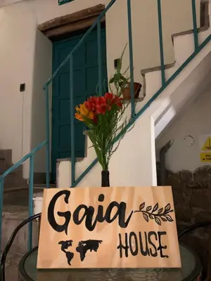 a sign on a table with a vase of flowers at Gaia House Hostel in Cusco