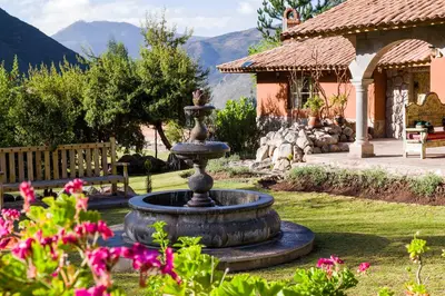 a fountain in the middle of a yard with flowers at VILLA APU CHICON (Apu Wasi & Inti Wasi) in Urubamba