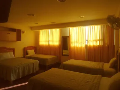 a hotel room with three beds and a window at Hotel Panamericano in Lima