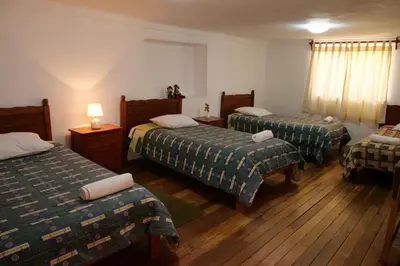 a hotel room with three beds in a room at Welcome Cusco Hostel in Cusco