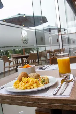 a plate of breakfast food on a table with a glass of orange juice at Tierra Viva Miraflores Centro in Lima
