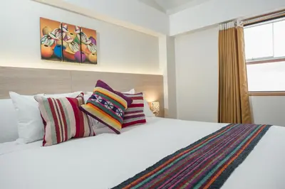 a bedroom with a large white bed with colorful pillows at Casa Matara Boutique in Cusco