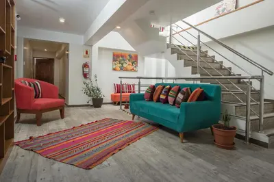 a living room with a blue couch and red chairs at Casa Matara Boutique in Cusco