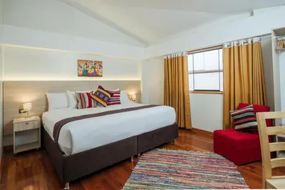 a bedroom with a large bed and a red chair at Casa Matara Boutique in Cusco