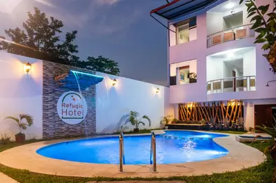 a villa with a swimming pool in front of a building at Refugio Hotel in San Ramón