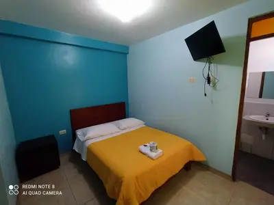 a bedroom with a bed with a yellow blanket at Hotel Villa Santa Ana in Quillabamba